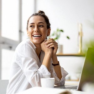 Woman in front of windows looking over shoulder smiling