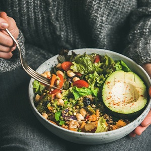 Hands forking salad from bowl in lap