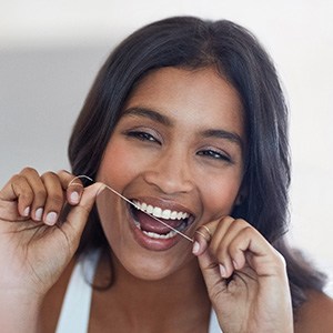 Woman smiling while flossing her teeth
