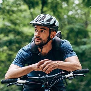 Man with helmet riding bike outside