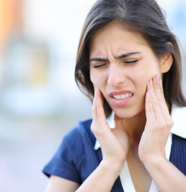 Woman suffering from jaw pain associated with TMJ disorder