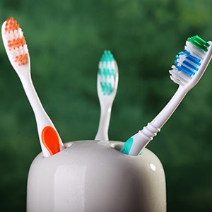 Three colored toothbrushes in a toothbrush holder
