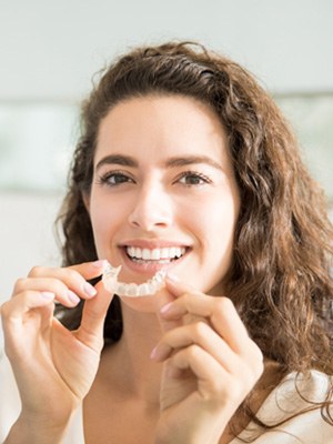 Woman smiling while holding clear aligner