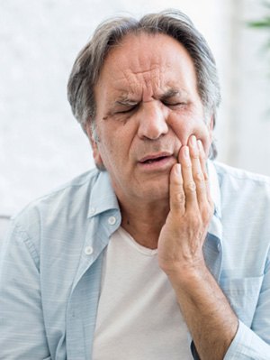 Man experiencing jaw pain at home