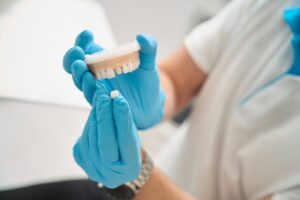 Dentist holding model of mouth with crown.
