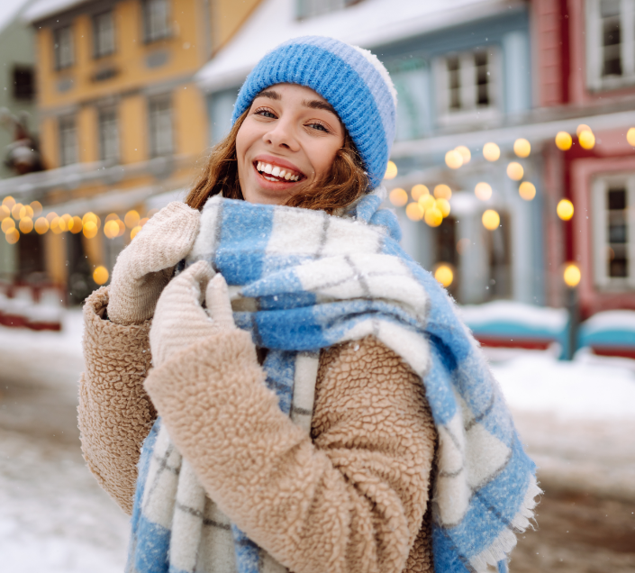 Smiling woman in scarf and hat standing on a snowy street