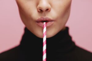 Pink and white straw resting on someone's lips