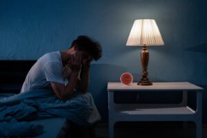 Man sitting up in bed during sleepless night.